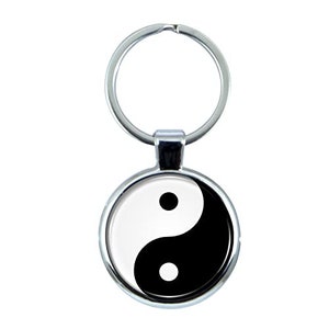 Puede incluir: Un llavero plateado con un dije redondo en blanco y negro que representa el símbolo del yin y el yang.