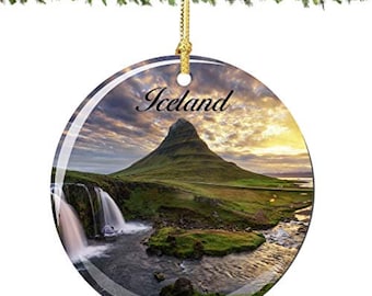 May include: Round glass ornament with a picture of a mountain range in Iceland. The ornament has a gold string for hanging and the text "Iceland" printed on it.