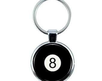 May include: A silver keychain with a round black and white 8-ball design. The 8-ball has a white number 8 on it.