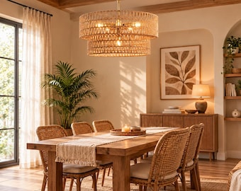 May include: A two-tiered drum chandelier featuring a woven rattan shade in a natural tan finish, suspended by a metal chain. The fixture houses multiple light bulbs that emit a warm glow, illuminating the surrounding dining room space.