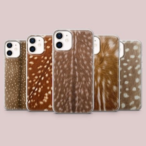 Peut inclure: Cinq coques de smartphone rectangulaires alignées, chacune présentant un motif de fourrure tacheté brun et blanc rappelant la peau de cerf. Les coques ont une bordure transparente et une découpe pour un double objectif photo en haut à gauche.