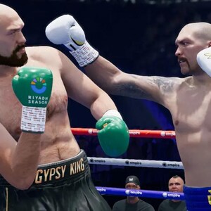 Może przedstawiać: Dwóch bokserów na ringu podczas walki. Jeden bokser ma zielone rękawice i czarne spodenki z napisem "GYPSY KING" na pasie. Drugi bokser ma białe rękawice oraz niebiesko-białe spodenki z napisem "USYK" widocznym na pasie.
