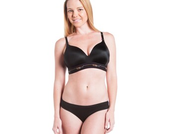 May include: A black wireless bra with adjustable straps and a black thong. The bra has the word "TOM" written on the band.