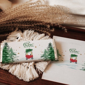 May include: A white chocolate bar wrapper with a watercolor illustration of a red toy car carrying a Christmas tree. The text on the wrapper reads "It's the most wonderful time of the year."
