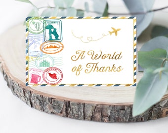 May include: A white card with a gold airplane and the text "A World of Thanks" in gold script. The card is decorated with colorful stamps of various cities and countries.