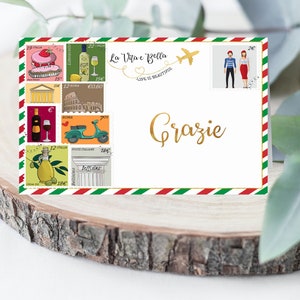 May include: A white card with a red, white and green border. The card features a collage of Italian-themed images, including a cake, a bottle of wine, a scooter and a lemon tree. The card also has a small image of a couple and a plane. The text "La Vita e Bella" and "Life is Beautiful" are printed on the card. The word "Grazie" is written in gold lettering on the card.