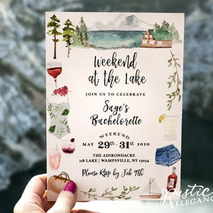 May include: A watercolor illustration of a lake cabin with mountains in the background. The text reads "Weekend at the Lake" and "Join us to celebrate Sage's Bachelorette" with the dates "May 29th-31st 2020". The text "The Adirondacks 118 Lake | Wampsville, NY 13034" and "Please RSVP by Feb 9th" are also included. The illustration includes various items such as a glass of wine, a swimsuit, a cocktail, a pair of denim shorts, a purse, and a sailboat.