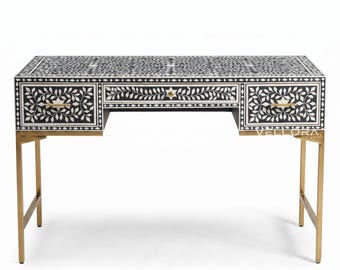 Escritorio artesanal con incrustaciones de hueso negro, patas con acabado de latón y diseño floral, tocador moderno para estudio.