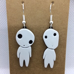 May include: A pair of white dangle earrings featuring a cartoon character with black eyes and a simple smile. The earrings are made of polymer clay and have silver hooks.
