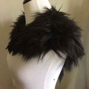 May include: A black faux fur collar with a long, shaggy texture. The collar is displayed on a white mannequin.