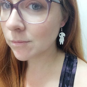 May include: A pair of silver earrings with a white, cartoon-like figure hanging from each earring.