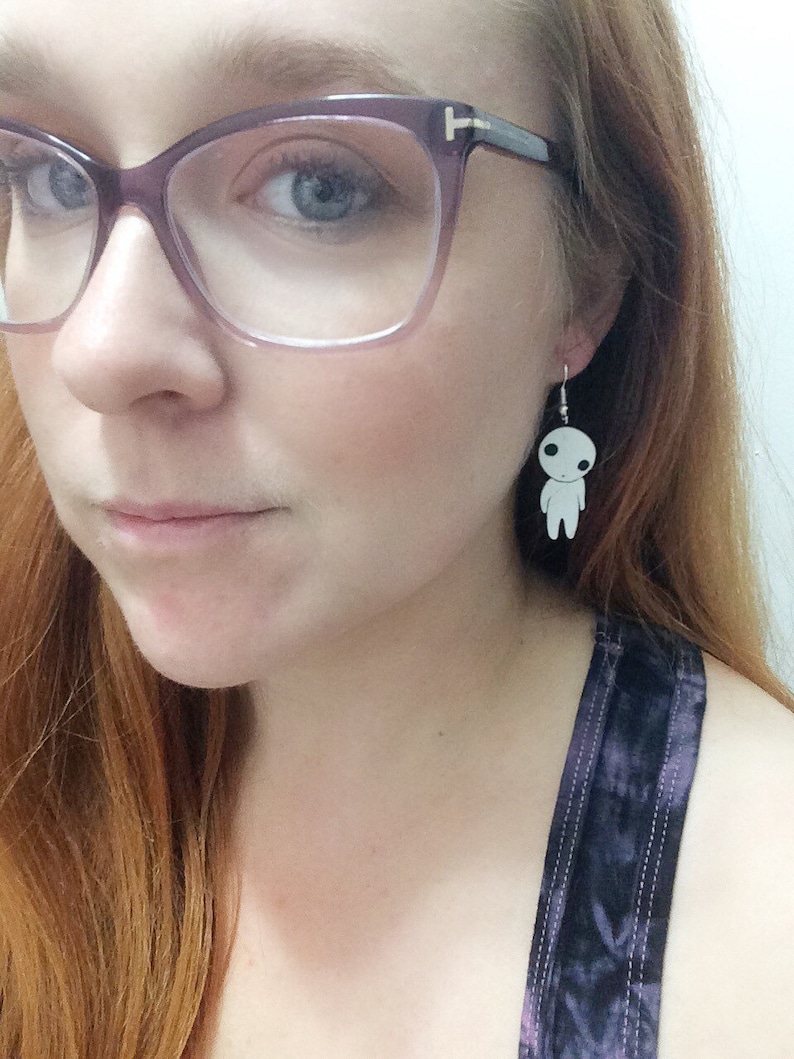 May include: A pair of silver earrings with a white, cartoon-like figure hanging from each earring.
