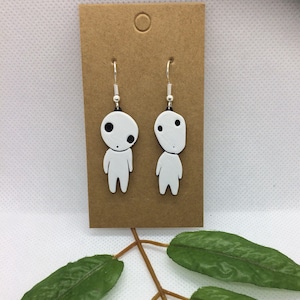 May include: White dangle earrings with a small white figure with black eyes on each earring.