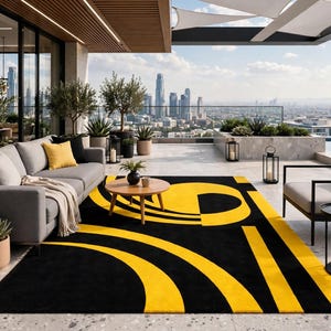 May include: A rectangular area rug featuring a bold geometric pattern of vibrant yellow curved lines and solid black shapes. The rug is positioned on a light-colored stone floor, providing a high-contrast visual element to the outdoor living space.