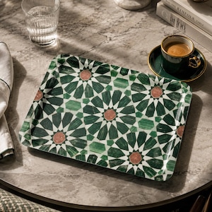 May include: A rectangular serving tray featuring a geometric star pattern in shades of dark green, light green, and white, with small octagonal accents in a muted reddish-brown color. The tray has slightly raised edges and a smooth, glossy finish.