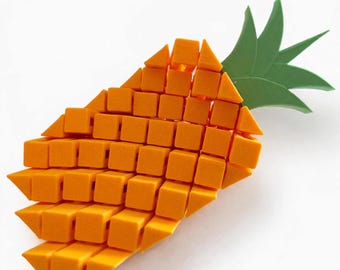 Op de afbeelding: Een ananasvormig object opgebouwd uit talloze kleine oranje kubussen en driehoekige prisma's, met een puntige groene bladstructuur aan de bovenkant. Het ontwerp creëert een geometrische, voxel-achtige weergave van de vrucht.