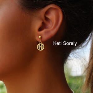 Peut inclure: Boucle d'oreille monogramme dorée avec les initiales EHG dans un design circulaire. La boucle d'oreille est suspendue à un petit clou doré. Le texte "Keti Sorely" est visible dans l'image.