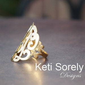 May include: A gold ring with a delicate, intricate design. The ring is made of a single piece of metal and has a unique, asymmetrical shape.