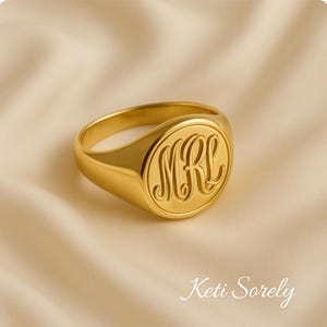 May include: A gold signet ring with a round, engraved top featuring the initials "MRL".