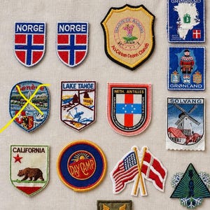 Puede incluir: Una colección de parches bordados con varios diseños. Incluye parches con la palabra "NORGE", un escudo con una flor, un parche de California con un oso, y parches con banderas y texto.