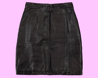 May include: A black leather skirt with a pencil silhouette. The skirt has a high waist and a straight hemline. Vertical seams run down the front and back, and the skirt is set against a light purple background.