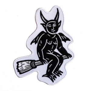 May include: Black and white embroidered patch of a devil sitting on a broomstick.