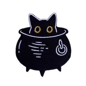 以下が含まれることがあります： 黒い鍋から顔を出している黒い猫。鍋の側面には白い電源ボタンがついている。猫は黄色い目をしている。