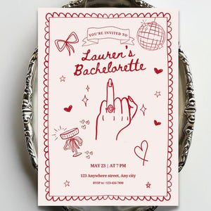 May include: A rectangular invitation card with a light pink background and red line art. It features a hand showing a middle finger with a ring, a disco ball, a bow, and hearts. Text reads: YOU'RE INVITED TO Lauren's Bachelorette MAY 23 | AT 7 PM.
