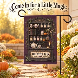 Peut inclure: Un drapeau de jardin violet illustrant une étagère en bois sombre remplie de bocaux, théières, livres, un chat noir et des citrouilles. Le texte indique "Come In for a Little Magic" en haut et "THE WITCH IS IN" sur une plaque en bas.