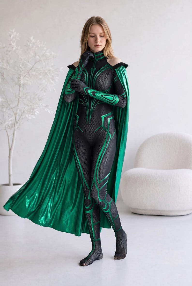 May include: A black and green full-body jumpsuit featuring a textured mesh pattern, long sleeves with cut-out shoulders, and a high collar. The garment includes a long, metallic green cape attached at the shoulders and matching green gloves.