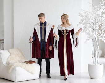 May include: A deep burgundy velvet cape with a white faux fur collar and a matching long-sleeved velvet gown featuring a white faux fur trim, gold chain accents, and a gold crown. The ensemble includes a silver sword and a gold-topped scepter.