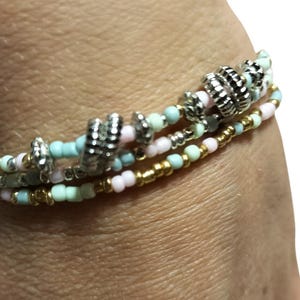 Pulsera triple de cuentas en tonos pastel, dorados y plateados con dijes. Joyería bohemia veraniega ajustable hecha a mano, pulsera original para mujer.