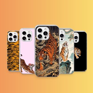 May include: Five smartphone cases featuring tiger-themed designs. One has an orange and black tiger stripe pattern, one is pink with a small tiger, one shows a tiger in stylized waves, one depicts a roaring tiger on a rock, and one is black with a tiger.