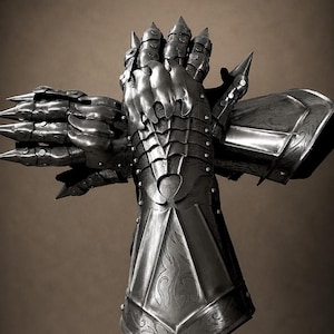 Peut inclure: Une paire de gantelets en acier articulé avec des plaques de doigts pointues, des segments métalliques superposés et des motifs de volutes gravés sur les manchettes. Les pièces d'armure présentent des rivets visibles et une finition polie.
