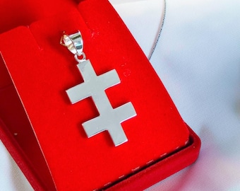 May include: A polished silver-toned pendant shaped like a double-barred cross, also known as a patriarchal cross. The pendant features a smooth, reflective metallic surface and is attached to a small silver-toned bail at the top for a chain.