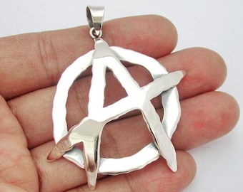 May include: A silver pendant in the shape of an anarchy symbol. The symbol is a circle with a stylized A inside.