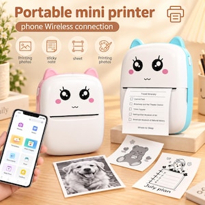 May include: Two portable mini printers with cat-ear designs, one pink and one blue, featuring cartoon faces. A smartphone displays a printing app interface. Printed items include a travel itinerary, a bear illustration, and a July plan sheet.