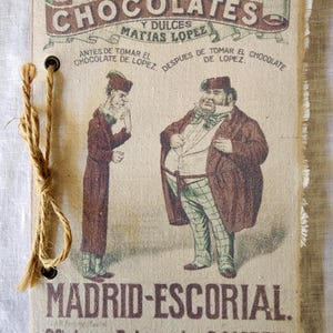 May include: A rectangular fabric-covered notebook with frayed edges, featuring a vintage illustration of two men and the text Chocolates y Dulces Matias Lopez, Madrid-Escorial, and Oficinas, Palma alta, 8 Madrid. A jute twine tie binds the left side.