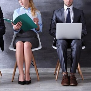 Peut inclure: Quatre personnes en tenue professionnelle sont assises sur des chaises blanches. Elles portent des costumes sombres, une chemise bleu clair avec une jupe grise, et un chemisier blanc avec un pantalon noir. Elles tiennent un dossier et un ordinateur.