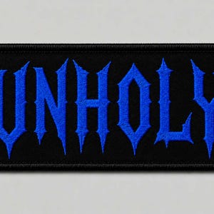 May include: A rectangular embroidered patch with a black background and a thick black border. The word UNHOLY is stitched in the center using bright blue thread in a sharp, jagged, gothic-style font with pointed edges on each letter.