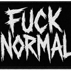 以下が含まれることがあります： 黒い背景に白い刺繍の文字で「FUCK NORMAL」と書かれた長方形の刺繍ワッペン。文字はギザギザとした擦れたようなフォントスタイルで、デザイン全体が太い黒い縁取りで囲まれています。