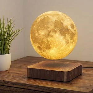 May include: A levitating moon lamp featuring a textured, spherical light orb with a realistic cratered surface, hovering above a square, dark wood-grain base with a power button symbol, emitting a warm, soft yellow glow in a room setting.