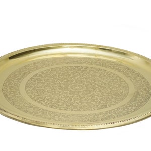 May include: A gold-colored, oval serving tray with an intricate floral pattern etched into the center. The tray has a beaded edge and a polished finish, suitable for decorative or functional use.