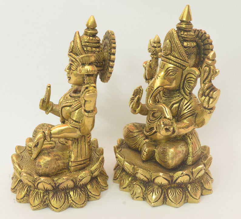 Peut inclure: Une paire de statues en m&eacute;tal dor&eacute; repr&eacute;sentant les divinit&eacute;s hindoues Ganesha et Lakshmi, assises sur des bases de fleurs de lotus. Les statues sont finement d&eacute;taill&eacute;es et pr&eacute;sentent un style indien traditionnel.