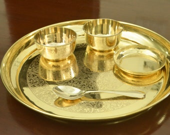 Puede incluir: Una bandeja de servir de metal dorado con un patrón decorativo. La bandeja incluye tres cuencos pequeños y una cuchara.