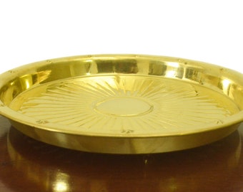 Puede incluir: Una bandeja redonda de metal dorada con un diseño decorativo de rayos de sol. La bandeja tiene un borde elevado y una superficie lisa y pulida.