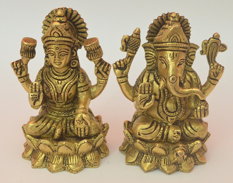 Peut inclure: Deux statues en m&eacute;tal dor&eacute; repr&eacute;sentant les divinit&eacute;s hindoues Lakshmi et Ganesha, assises sur des bases en forme de lotus. Les statues sont finement d&eacute;taill&eacute;es et pr&eacute;sentent un style indien traditionnel.