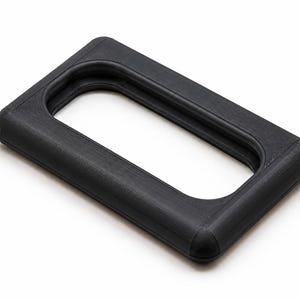 May include: A black rectangular frame with rounded corners and a central open aperture. The object features a textured surface with visible horizontal lines throughout its structure, indicating a layered construction process for this solid frame.