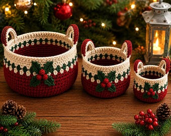 May include: A set of three round, crocheted baskets in descending sizes, featuring a deep red base, a cream-colored upper section, and a green and white patterned border. Each basket has two small handles and a decorative holly leaf and berry motif.