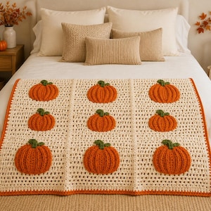 May include: A rectangular crochet blanket featuring a cream-colored grid pattern with nine raised, textured orange pumpkins with green stems arranged in three rows. The blanket is finished with a solid orange border along the outer edges.
